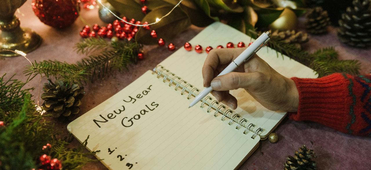 Man writing New Year's resolutions in a notebook