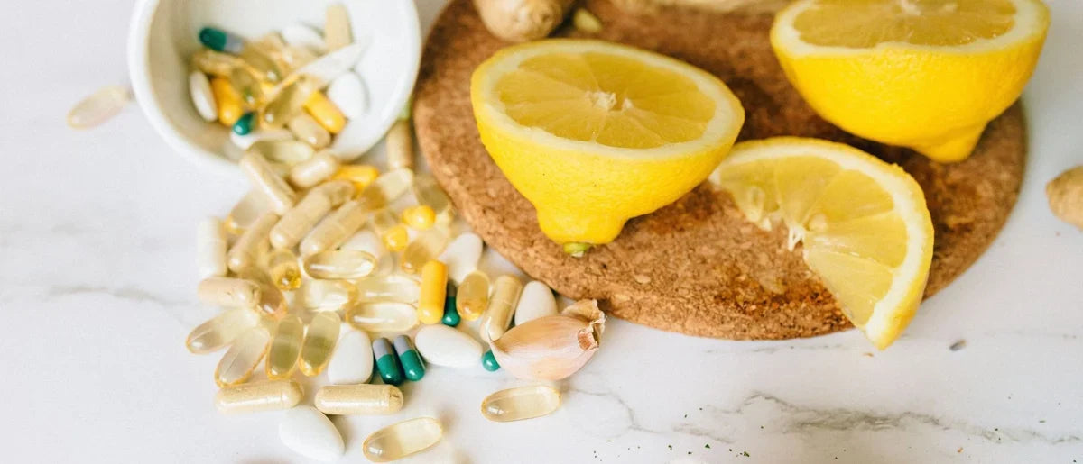 Immune support supplements and vitamins scattered on a countertop next to a sliced lemon