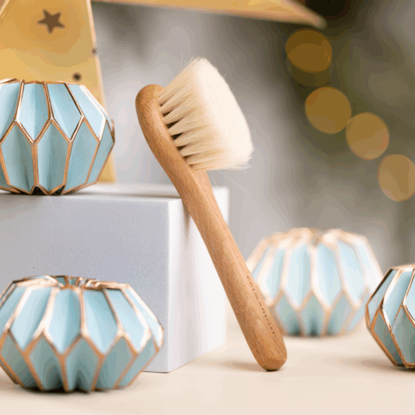 Primabiotic wooden facial massage brush with soft natural bristles placed vertically among decorative turquoise and gold candle holders